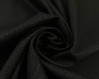 Könnte beinhalten: Nahaufnahme eines eng gerollten, strukturierten schwarzen Stoffstücks. Der Stoff scheint ein mittelschweres Material mit sichtbaren diagonalen Webstrukturen zu sein. Die tiefschwarze Farbe deutet auf einen vielseitigen Stoff hin.