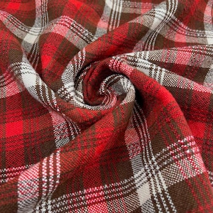Op de afbeelding: Close-up van een rood, bruin en wit geruite stof. De stof is strak geweven met een klassiek ruitpatroon. Het materiaal is gevouwen en gedrapeerd, waardoor de textuur- en kleurvariaties zichtbaar zijn.
