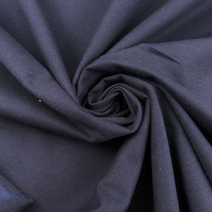 Peut inclure: Gros plan sur un tissu bleu marine avec une texture et des plis visibles. Le tissu est tissé serré, créant une surface lisse. L'image met en évidence la profondeur et la texture du matériau, adapté à l'habillement ou à la décoration intérieure.