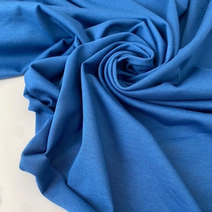 Könnte beinhalten: Nahaufnahme eines leuchtend blauen Stoffes, kunstvoll drapiert und gewirbelt. Der Stoff hat eine weiche, matte Oberfläche mit sichtbarer Textur und Falten. Die Farbe ist ein sattes, gesättigtes Blau, das einen dynamischen visuellen Effekt erzeugt.
