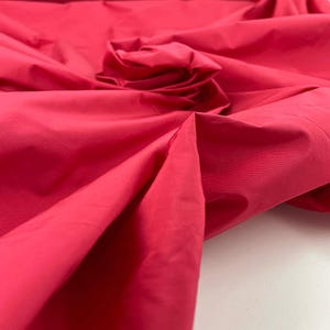 Puede incluir: Primer plano de una tela de color rosa brillante, mostrando su textura y caída.