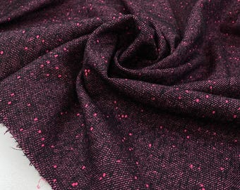 May include: Close-up of a dark burgundy fabric with a woven texture. The fabric has a speckled pattern of small, bright pink dots scattered across its surface. The material is folded, showing the texture and color variations.