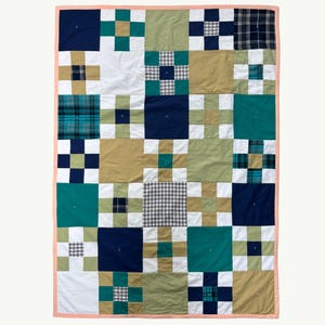 May include: A patchwork quilt in blue, green, tan, and white. The quilt has a repeating pattern of squares and rectangles, with a pink border. The quilt measures approximately 152 cm by 203 cm.