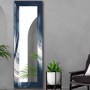 Puede incluir: Un espejo de pared rectangular y alto con un marco azul oscuro que presenta un patrón de mármol blanco con remolinos. La superficie del espejo refleja una planta verde y un elemento arquitectónico arqueado, creando un efecto visual.