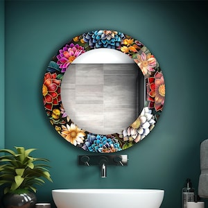 May include: A round floral mirror with a colorful flower border, mounted on a teal wall above a white sink. The mirror's frame features red, blue, yellow, and white flowers. The bathroom has a wooden countertop and a potted plant.