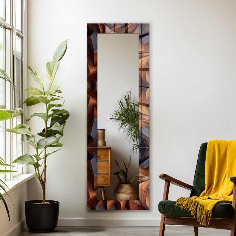 Pode incluir: Um espelho de corpo inteiro com uma moldura abstrata em tons de marrom, cinza e azul. O espelho est&aacute; pendurado em uma parede branca em um quarto com uma planta verde, uma c&ocirc;moda de madeira e uma poltrona verde com uma manta amarela.