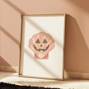 May include: A framed print of a seashell with a carved jack-o'-lantern face. The shell is a light orange colour with a white background.