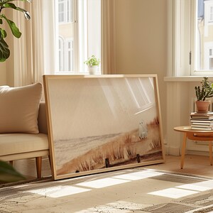 May include: A framed print of a watercolor painting depicting a beach scene with two figures in the distance. The painting is in shades of brown, beige, and white, with a soft, dreamy feel.