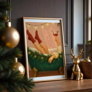 May include: A framed art print depicts a person relaxing in a green clawfoot bathtub, wearing red socks and holding a cocktail. The artwork is framed in gold and decorated with string lights. A gold deer figurine and a woven basket sit on a wooden surface.