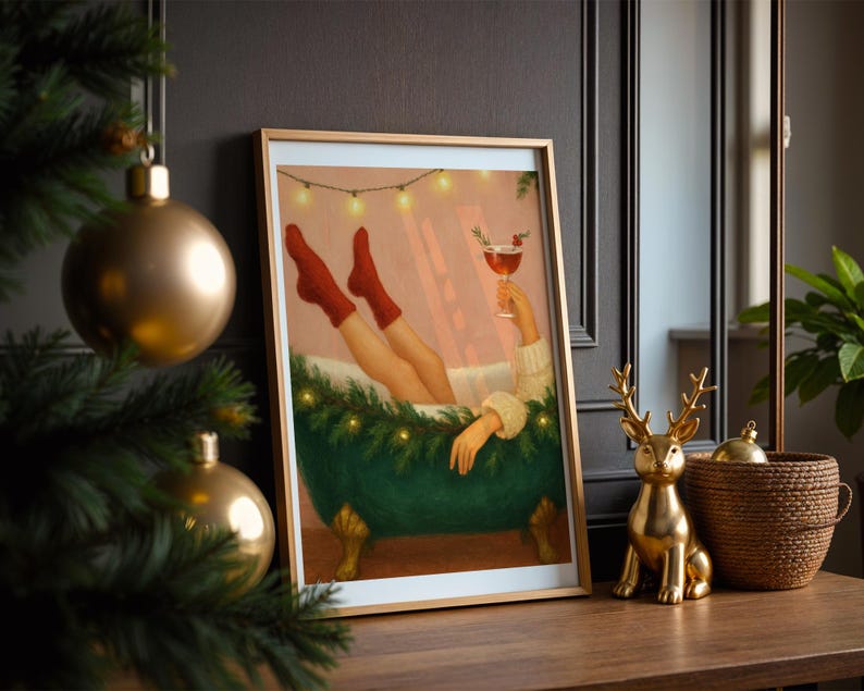 May include: A framed art print depicts a person relaxing in a green clawfoot bathtub, wearing red socks and holding a cocktail. The artwork is framed in gold and decorated with string lights. A gold deer figurine and a woven basket sit on a wooden surface.
