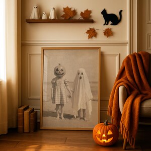 May include: A framed sepia photograph of two children in Halloween costumes, one with a pumpkin head and the other in a ghost costume. A carved pumpkin with a lit face sits on the floor. Decorative ghosts and a black cat are on the wall.