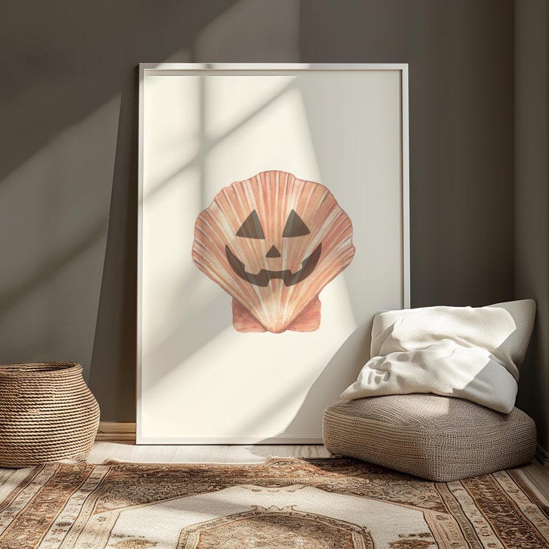 May include: A framed print of a seashell with a carved jack-o'-lantern face. The shell is a light orange colour with a white background.