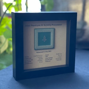 May include: Framed Intel Pentium III SL5GQ Processor. The processor is displayed on a tan background with technical specifications. The frame is black, and the text "Released in July 2001" is visible. The processor is a square with a grid of small dots.