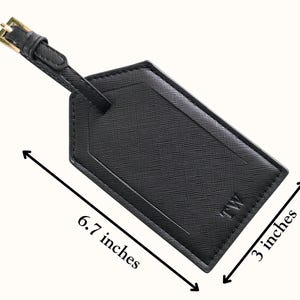 May include: Black luggage tag with a gold buckle and strap. The tag is 6.7 inches long and 3 inches wide. The tag has the initials "TW" on the bottom right corner.