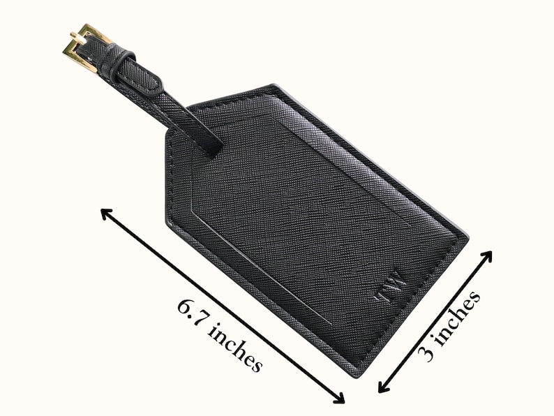 May include: Black luggage tag with a gold buckle and strap. The tag is 6.7 inches long and 3 inches wide. The tag has the initials "TW" on the bottom right corner.