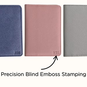 May include: Three personalized passport holders in navy blue, blush pink, and gray. Each holder features embossed initials: "JOR", "VKL", and "MQ". The image highlights the precision blind emboss stamping technique used for the personalization.