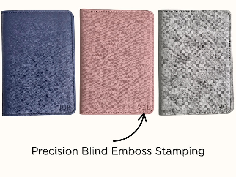 May include: Three personalized passport holders in navy blue, blush pink, and gray. Each holder features embossed initials: "JOR", "VKL", and "MQ". The image highlights the precision blind emboss stamping technique used for the personalization.