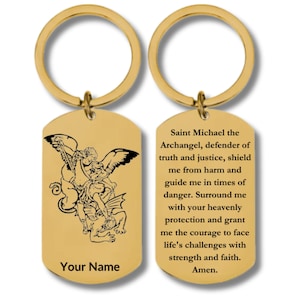 May include: A gold-toned metal keychain featuring a rectangular tag with rounded corners. One side displays a black engraved illustration of Saint Michael the Archangel and the text Your Name. The reverse side features a prayer to Saint Michael.