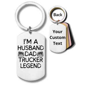 Könnte beinhalten: Ein silberfarbener Schlüsselanhänger mit einem großen Ring und einem Anhänger in Form einer Hundemarke. Der Anhänger trägt den schwarzen Text "I'M A HUSBAND DAD TRUCKER LEGEND". Ein kleineres Schild mit "Your Custom Text" ist ebenfalls sichtbar.