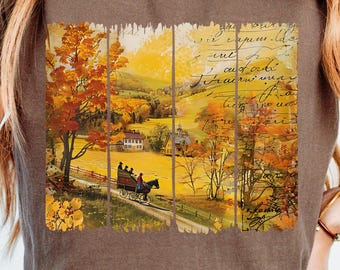 May include: Brown t-shirt featuring a vintage autumn scene with a horse-drawn carriage on a road, surrounded by trees with orange and yellow leaves. The graphic has a distressed, aged look, evoking a sense of nostalgia. The shirt is paired with blue jeans.