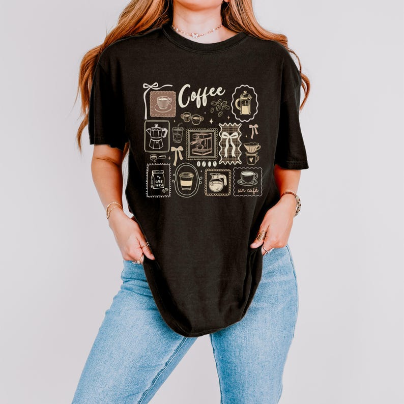 May include: Black t-shirt with a coffee-themed design. The design includes various coffee-related illustrations such as a coffee cup, coffee pot, and coffee beans, along with the word "Coffee". The shirt is paired with blue jeans.