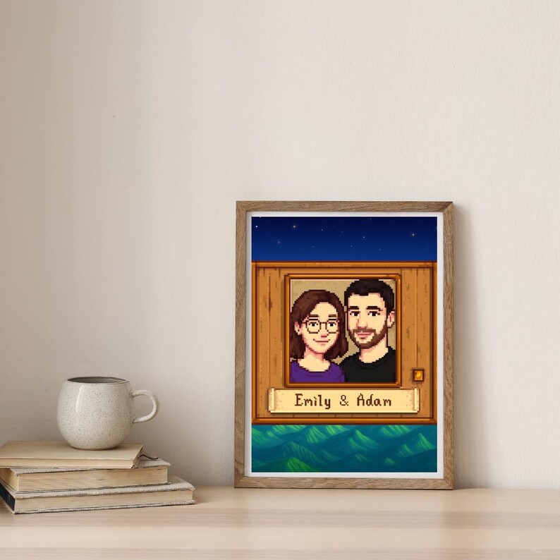 May include: A framed pixel art portrait of a couple, Emily and Adam, set against a wooden background with a starry sky. The artwork is displayed on a wooden table with a mug and books.