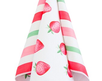 May include: A white kitchen towel with a pink and green striped pattern on one side and a strawberry print on the other side. The towel is hanging from a silver hook.