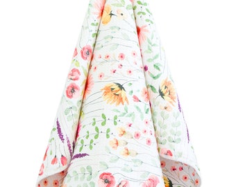 May include: A white kitchen towel with a floral pattern featuring pink, orange, and green watercolor flowers. The towel is hanging from a silver hook.