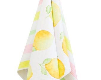 May include: A white kitchen towel with a lemon print. The towel has pink, green, and yellow stripes. The towel is hanging on a hook.