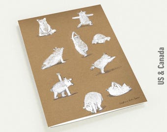 May include: A brown notebook featuring whimsical illustrations of white bears in various yoga poses. The notebook has a white border and the text "US & Canada" is visible on the right side.