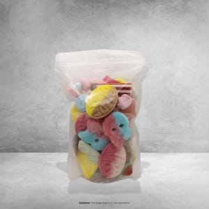 Puede incluir: Una bolsa de plástico transparente llena de una variedad de caramelos de goma coloridos. Los caramelos incluyen formas como corazones, conos de helado y caras, en tonos de rosa, amarillo, azul y rojo. La bolsa está sellada en la parte superior y se encuentra sobre una superficie blanca.