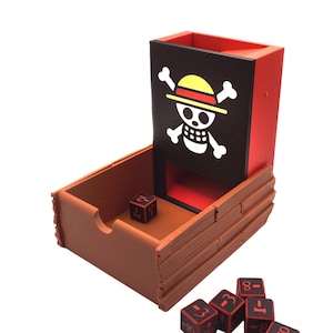 May include: A brown wooden dice tower with a red interior and a black panel featuring a white skull and crossbones logo. Several black dice with red numbers are scattered around the tower.