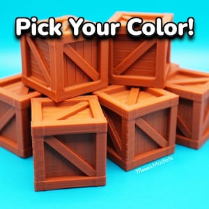 Puede incluir: Un conjunto de pequeñas cajas de madera marrón apiladas sobre una superficie azul brillante. Las cajas tienen un diseño clásico con soportes diagonales y el texto "Pick Your Color!" en blanco.