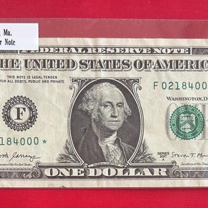 Op de afbeelding: Een briefje van één dollar met een portret van George Washington. Het briefje is een ster-briefje met het serienummer F02184000. Het briefje is in goede staat en heeft een groene zegel.