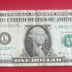 May include: A one dollar bill featuring a portrait of George Washington. The bill is in good condition and has the serial number L 00021567. The bill is a Federal Reserve Note and is legal tender for all debts, public and private.