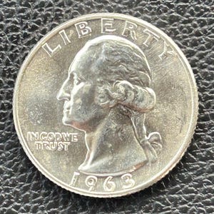 Può includere: Una moneta da un quarto di dollaro americano in argento con l'anno 1963 inciso sul fondo. La moneta presenta un profilo di Lady Liberty con le parole "LIBERTY" sopra e "IN GOD WE TRUST" sotto.