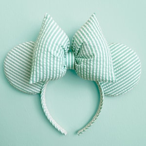 May include: Green and white striped fabric Minnie Mouse ears headband with a large bow.