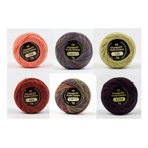 May include: Six spools of WonderFil Perle Cotton embroidery thread in various colors. The spools are labeled with the thread number and weight. The colors include orange, purple, green, red, multi-colored, and dark purple.