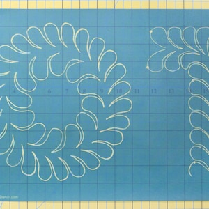 May include: A blue quilting stencil featuring a circular design and a corner design, both with a repeating white teardrop pattern. The stencil has a grid pattern and measurements in inches.