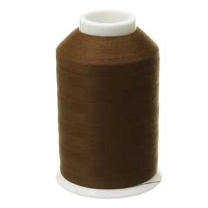 May include: A spool of brown thread with a white plastic bobbin.