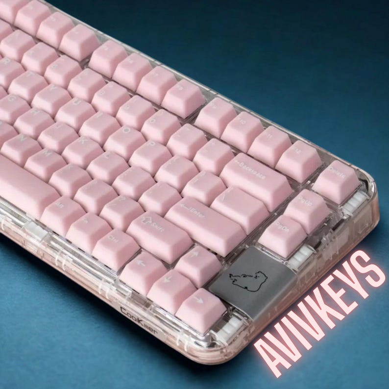 May include: A pink mechanical keyboard with clear casing. The keyboard has pink keycaps and a gray spacebar with a small graphic. The text "AVIVKEYS" is visible in the bottom right corner.