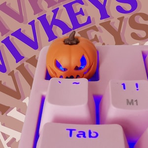 Peut inclure: Un clavier mécanique rose avec un capuchon de touche en forme de citrouille. Le clavier est rétroéclairé en bleu et le capuchon de touche est éclairé de l'intérieur. Le capuchon de touche est une décoration sur le thème d'Halloween pour un clavier.