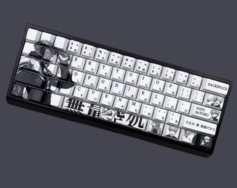 May include: A black and white keyboard with a custom keycap set featuring characters from the anime Jujutsu Kaisen. The keycaps have Japanese characters and the text "GOJO SATORU" and "大丈夫 僕最強だから".