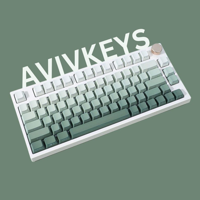 Op de afbeelding: Een wit mechanisch toetsenbord met een groen gradi&euml;nt toetsenontwerp. De keycaps gaan over van wit naar verschillende groentinten. Het woord "AVIVKEYS" staat in witte letters bovenaan het toetsenbord.