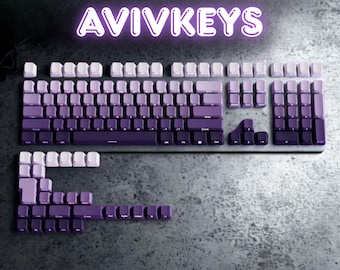 May include: A keyboard with keycaps in a gradient of purple hues, from light lavender to deep violet. The keyboard is displayed with some keycaps removed and arranged separately. The word "AVIVKEYS" is written in a glowing purple font above the keyboard.