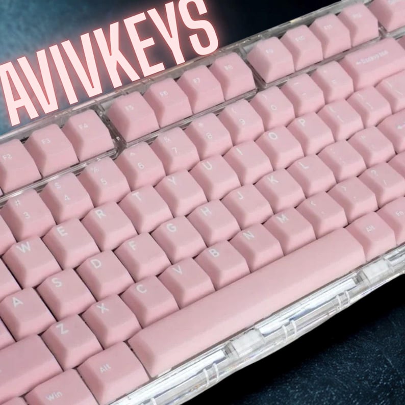 May include: A close-up of a mechanical keyboard with pink keycaps. The keyboard has a clear, transparent frame. The keys are arranged in a standard QWERTY layout. The word "AVIVKEYS" is displayed in a light pink font at the top.