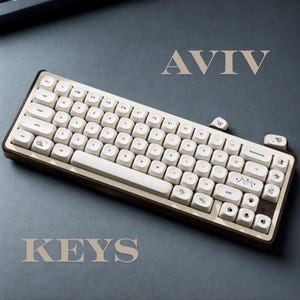 May include: A cream-colored mechanical keyboard with brown trim and white keycaps. The keyboard has the word "AVIV" above it and "KEYS" below it. Some keycaps feature paw prints and cat illustrations.