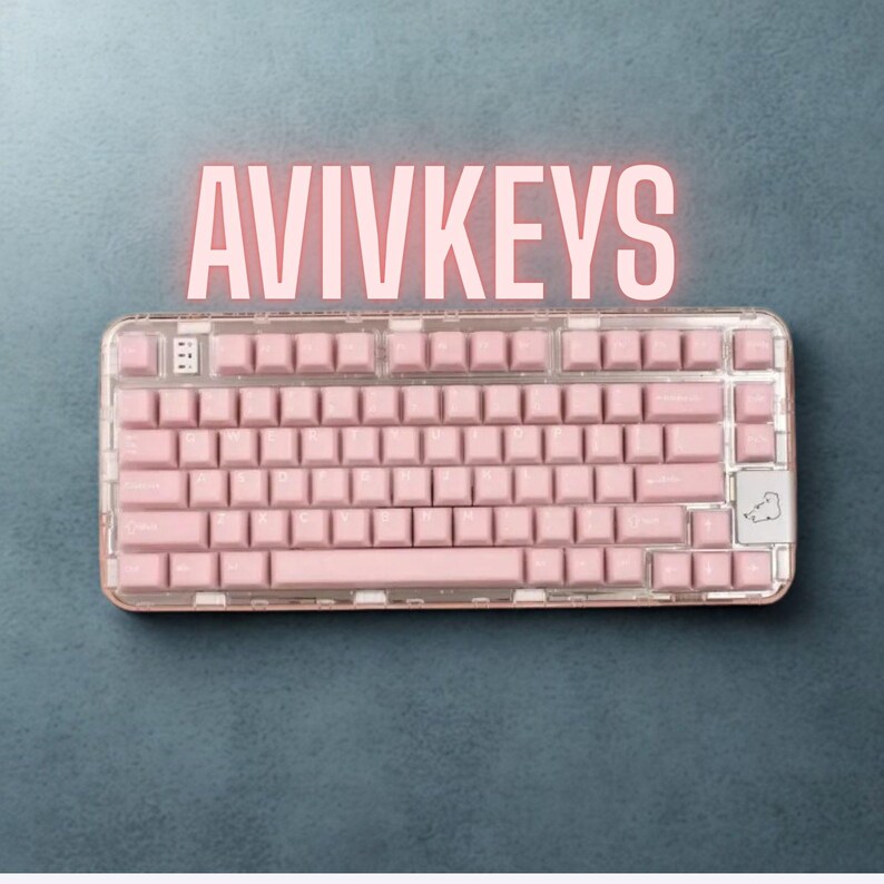 May include: A pink mechanical keyboard with a clear frame and pink keycaps. The keyboard has the text "AVIVKEYS" in a pink, glowing font above it. The keyboard is on a dark blue surface.