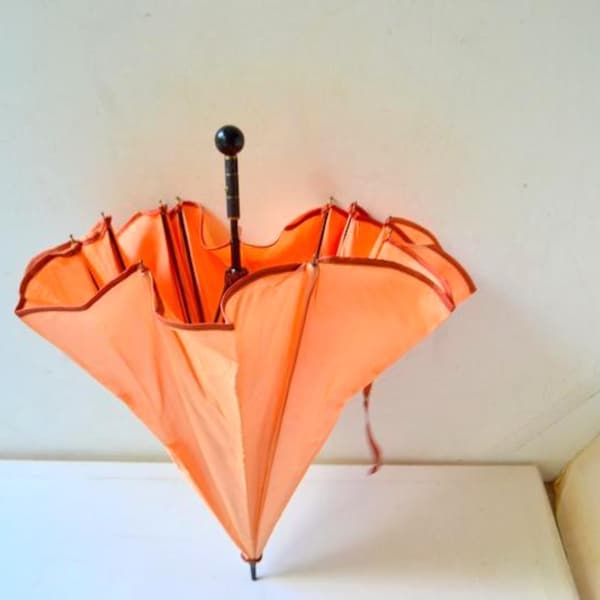 Parapluie pour enfant en nylon pêche 1950 avec bords festonnés, manche court noir, extrémité en forme de boule.