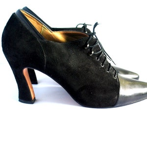 May include: Black suede and leather ankle boots with a lace-up front and a high block heel.